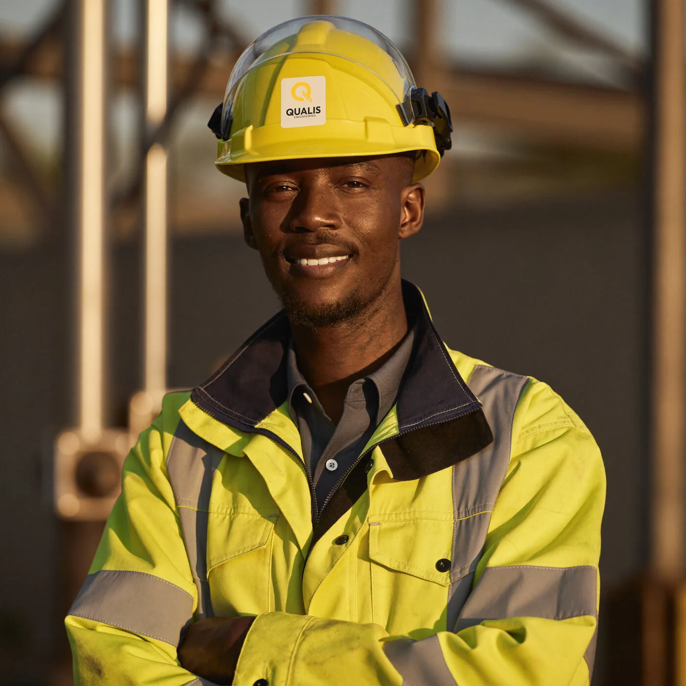 A Qualis engineer in branded hi-vis and helmet at golden hour